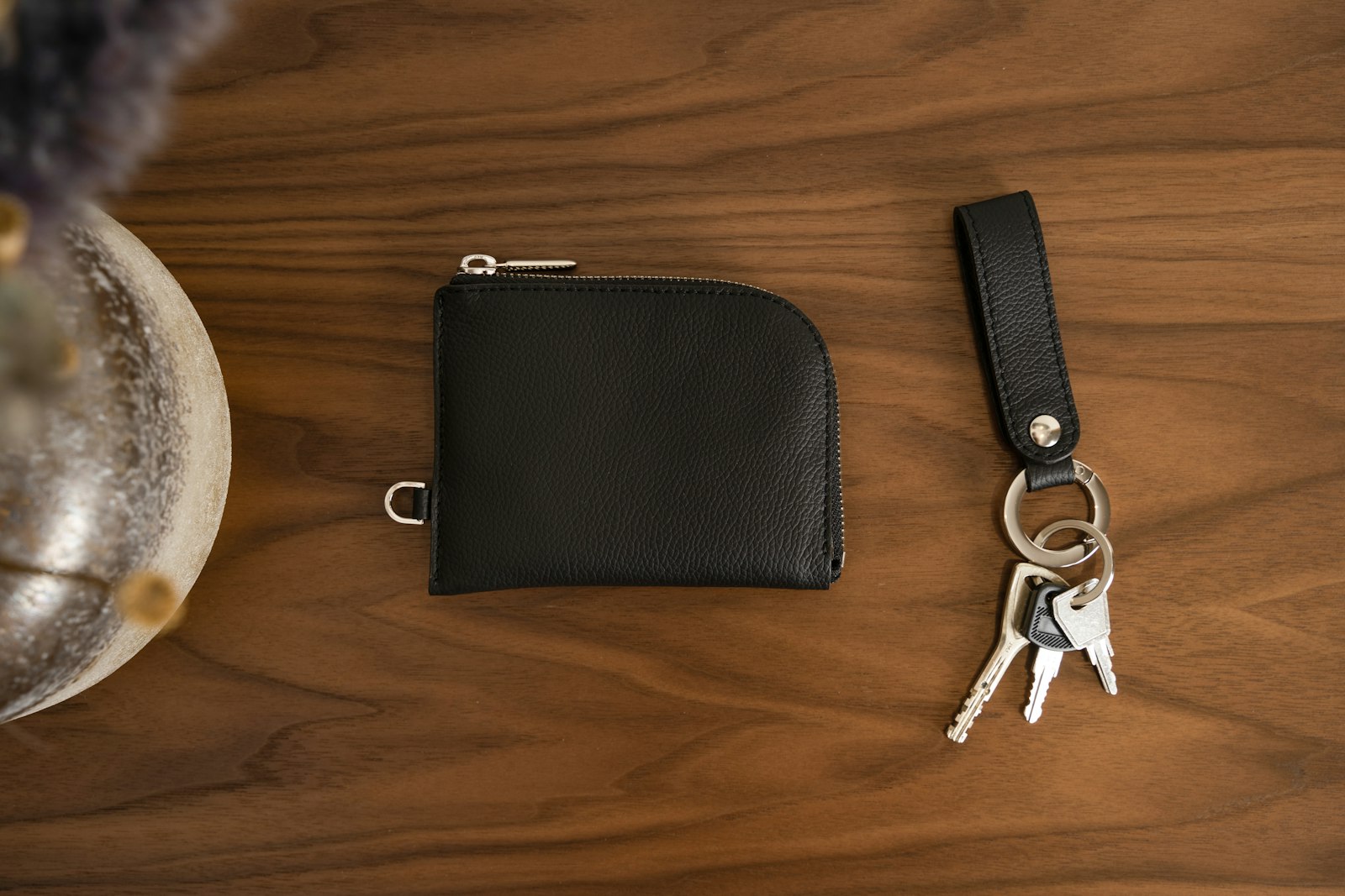 Handmade black leather wallet and keychain on a walnut table